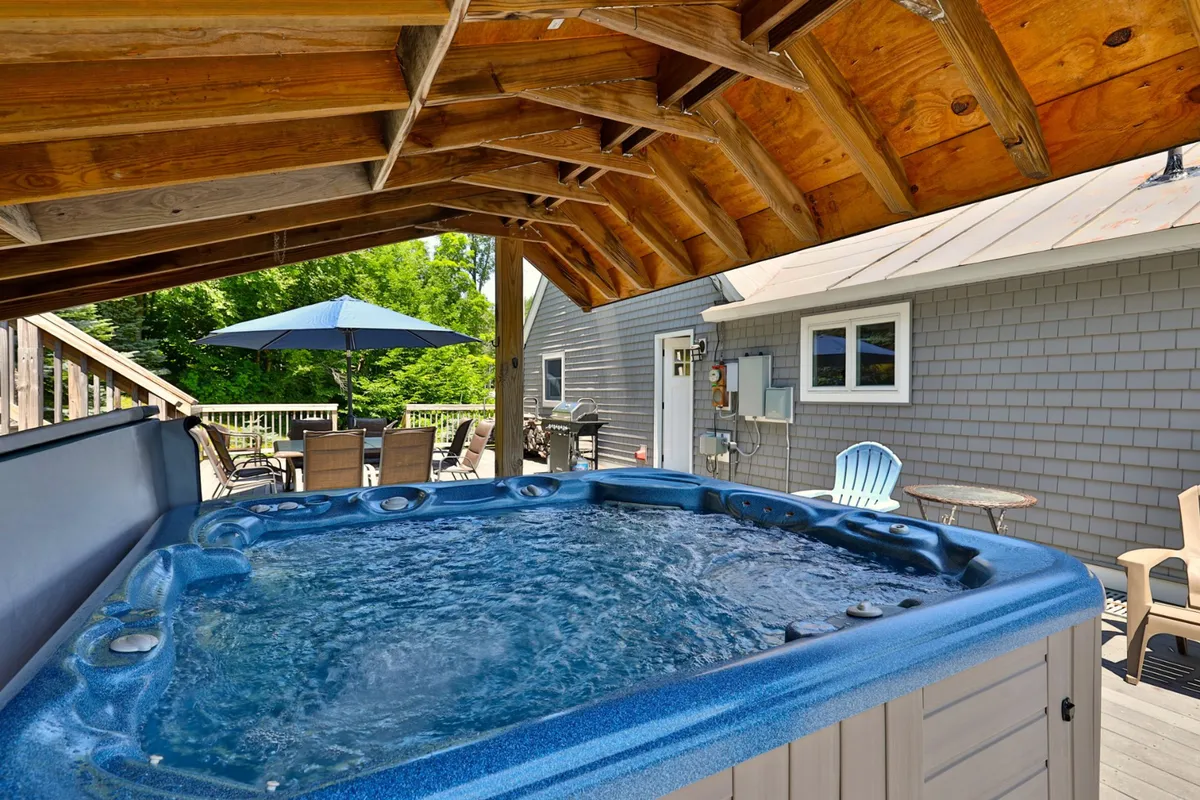 An inviting outdoor hot tub, surrounded by seating and wooden beams, with views that suggest relaxation in a natural setting. The mood is one of comfort and enjoyment after a day outdoors.