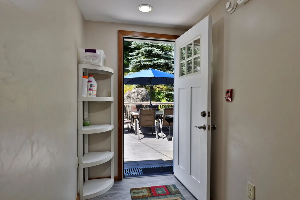 A view from the interior toward an open doorway leading onto a patio, seamlessly connecting indoor living with outdoor enjoyment. The patio area invites guests to step outside for coffee or playtime with their dogs, while the interior remains welcoming and homey.